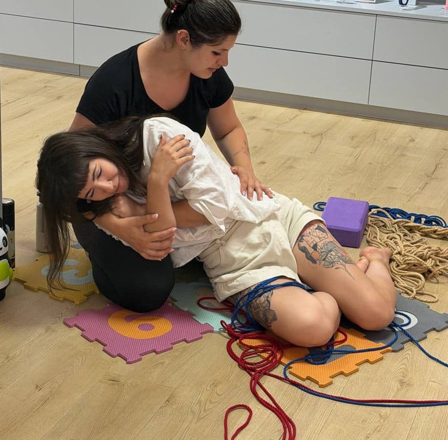 Messalina tient une élève contre elle pendant un atelier ; l'élève a les yeux fermés et sourit, apaisée